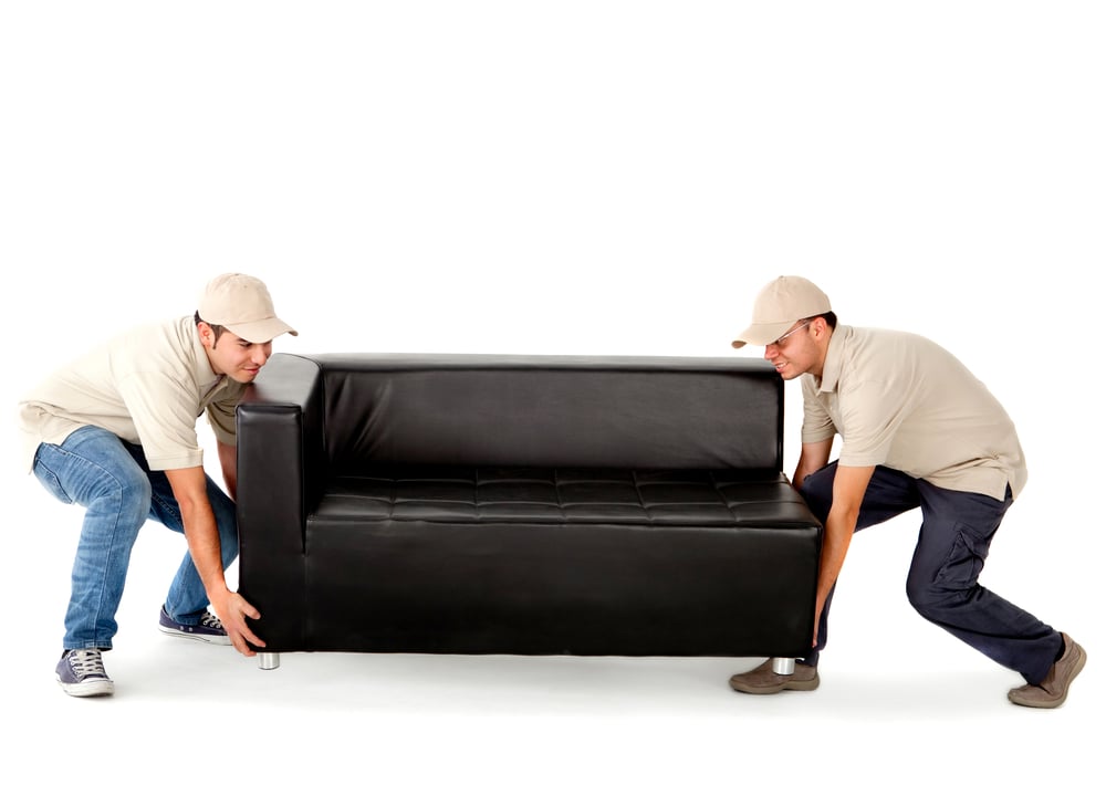 Delivery men carrying a big sofa - isolated over a white background